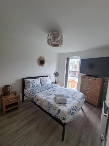 a bedroom with a bed with a blue and white comforter at lovely new home in manchester close to MANCHESTER CITY FC in Manchester
