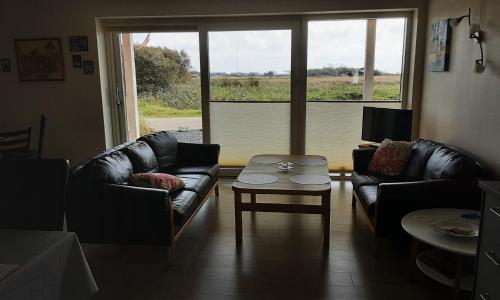 a living room with couches and a table and a window at Villa-Amby in Ringkøbing