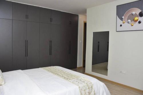 a bedroom with a white bed and a mirror at Blissful Airport Serviced Apt. in Nairobi