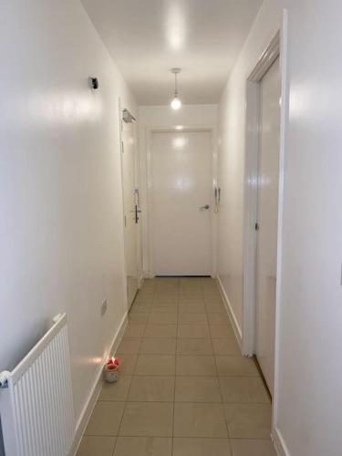 a hallway with a white door and a tile floor at Comfort Luxe in Hatch End