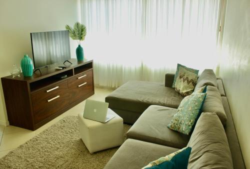 ein Wohnzimmer mit einem Sofa und einem Laptop darauf in der Unterkunft La Menina Mole Beachfront House! 4BR/4,5Baths in Florianópolis