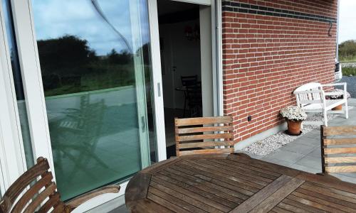 a porch with a wooden table and two chairs at Villa-Amby in Ringkøbing