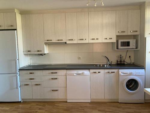 a kitchen with white cabinets and a washer and dryer at Bonito apartamento en Ezcaray in Azarrulla
