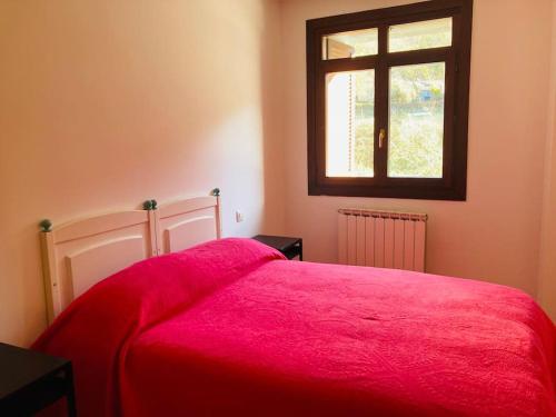 um quarto com uma cama vermelha e uma janela em Bonito apartamento en Ezcaray em Azarrulla