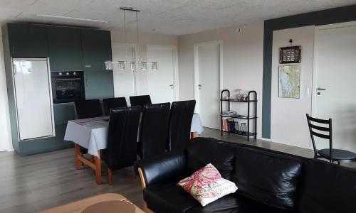 a living room with a black leather couch and a table at Villa-Amby in Ringkøbing