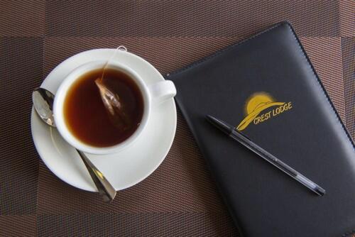 een kopje koffie op een bord naast een boek bij The Crest Lodge Limited in Lusaka