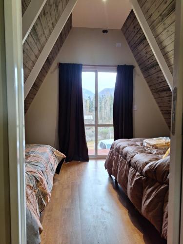 a bedroom with two beds and a large window at Cabañas Alpinas in Mendoza