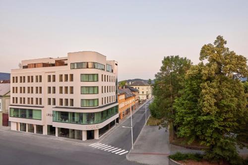 ein hohes weißes Gebäude in einer Stadtstraße mit Bäumen in der Unterkunft Hotel PERK in Šumperk