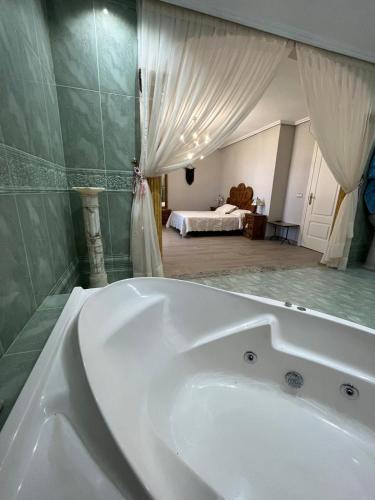 a white bath tub in a bathroom with a bedroom at Villa Nogueroles in Sanchidrián