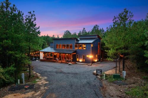 a large house in the woods at dusk at Unwind in Style! *NEW* Sip and Stay Hideaway in Broken Bow