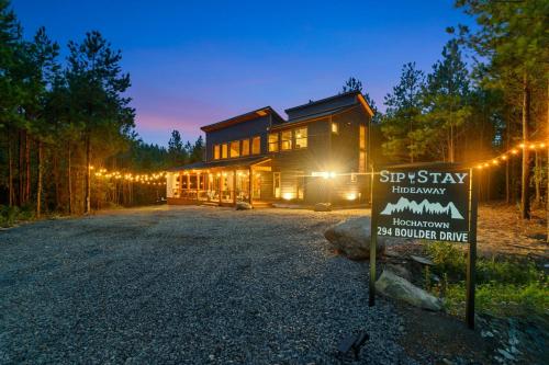 a sign in front of a wooden house at night at Unwind in Style! *NEW* Sip and Stay Hideaway in Broken Bow