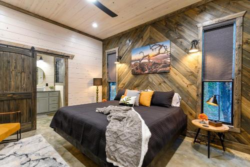 a bedroom with a bed in a room with wooden walls at Unwind in Style! *NEW* Sip and Stay Hideaway in Broken Bow