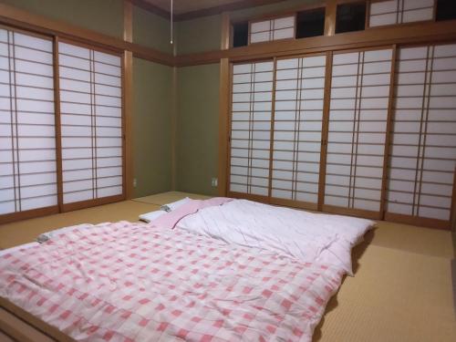 una camera con un letto in una stanza con finestre di BANRYU 萬龍 バンリュウ a Iida