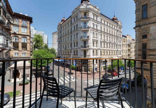 einen Balkon mit Stühlen und eine Straße mit Gebäuden in der Unterkunft Sophia Hotel Kyiv in Kiew