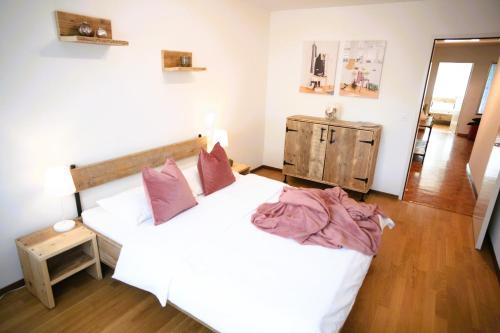 - une chambre avec un lit doté de draps blancs et d'oreillers roses dans l'établissement Nest - Hertizentrum 2, à Zoug
