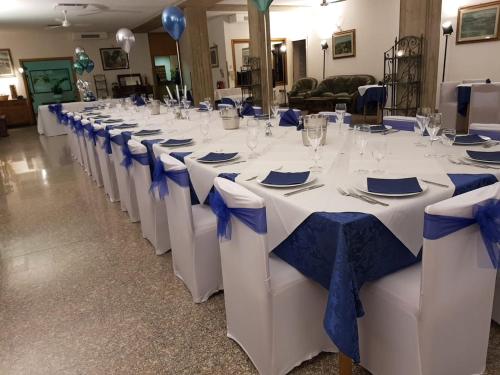 a row of white tables with blue bows on them at Da Beppe in Chiesina Uzzanese