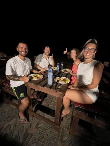 a group of people sitting at a table eating food at Wadi Rum Desert Adventures in Wadi Rum
