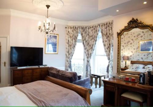 a bedroom with a bed and a tv and a mirror at East Beach Hotel in Eastbourne