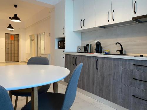 cocina con mesa blanca y sillas azules en Studios & Apartments Palas by GLAM APARTMENTS en Iaşi