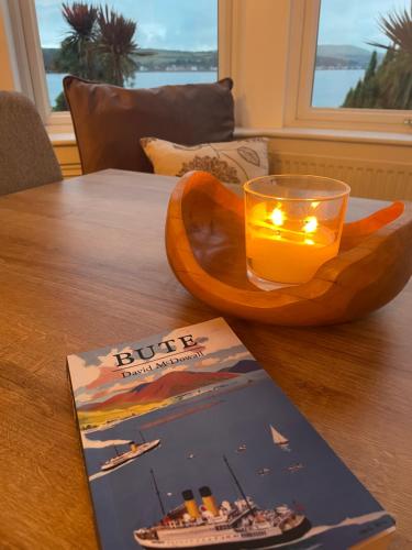 a book and a candle on a table with a book at Bayside - Breathtaking views of the Clyde in Rothesay