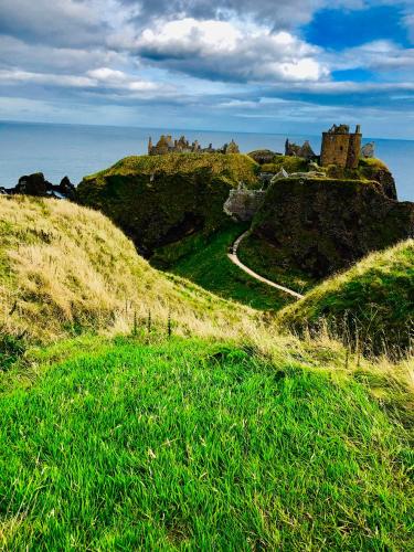 a castle on top of a hill with green grass at Stoney Hideaway in Stonehaven