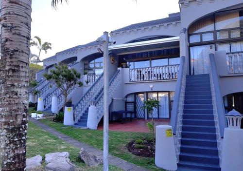 a building with blue stairs and a palm tree at Uvongo cabanas in Margate
