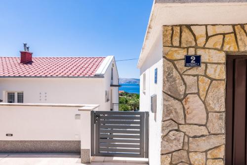 a white house with a gate and a stone wall at Apartmani Katica in Povile