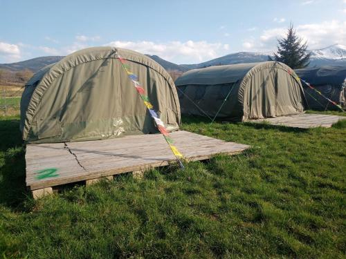 dwa namioty na polu z drewnianą deską w trawie w obiekcie Camp66 w mieście Karpacz