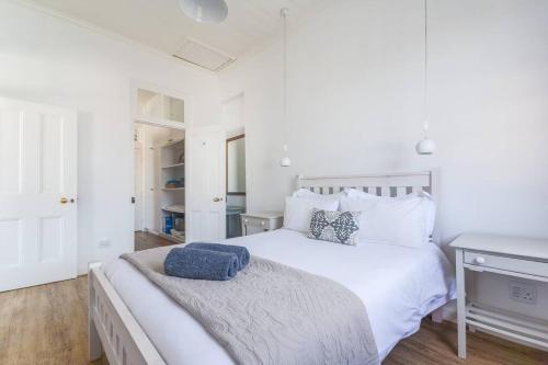 a white bedroom with a large white bed and a desk at Sunny Windsor Apartment in Kalk Bay in Cape Town