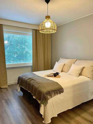 Schlafzimmer mit einem Bett mit einem Fenster und einem Kronleuchter in der Unterkunft Upea Skandinaavinen Luksushuoneisto Nokia-Areenan vieressä in Tampere