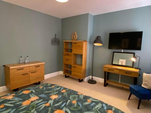 a bedroom with a bed and a desk and a television at Brooklands Guest House in Llandrindod Wells