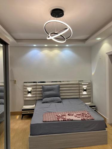 - une chambre avec un grand lit et un lustre dans l'établissement Modern flat 3 rooms and 2 bathroom amazing location شقة فندقية حديثة و جديدة كاملة مدينة نصر بالقرب من ستي ستارز 2 غرف نوم 2 حمام وصالة و بلكونة, au Caire