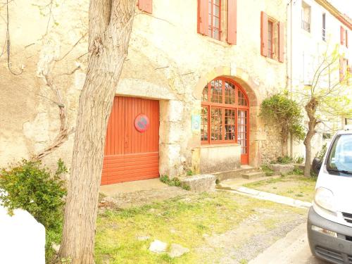 une maison avec une porte rouge et une voiture garée devant dans l'établissement GîTE-FAMILLE NOMBREUSE-SÉMINAIRE-PATIO, à Ornaisons