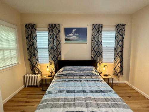 a bedroom with a bed and two windows at Lord Medford Apartments in Medford
