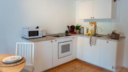 uma pequena cozinha com armários brancos e um micro-ondas em Montana - Ferienwohnung am Laber em Oberammergau