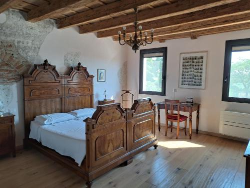 Un dormitorio con una gran cama de madera y una mesa. en Corte Ramedello, en Cerea