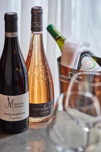 two bottles of wine on a table with a glass at Boutet Bastille Hotel Paris - MGallery Collection in Paris