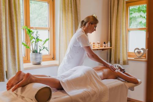 uma mulher a receber uma massagem de um homem numa cama em Relax- & Wanderhotel Poppengut em Hinterstoder