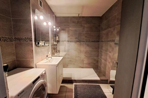 ein Badezimmer mit einem Waschbecken und einer Waschmaschine in der Unterkunft Airport Access Apartment - Your Gateway to Comfort in Charleroi