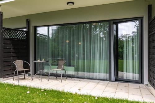 a screened in porch with two chairs and a table at Hotel Solny Studio z Tarasem, BASEN & SPA Kołobrzeg by Renters in Kołobrzeg