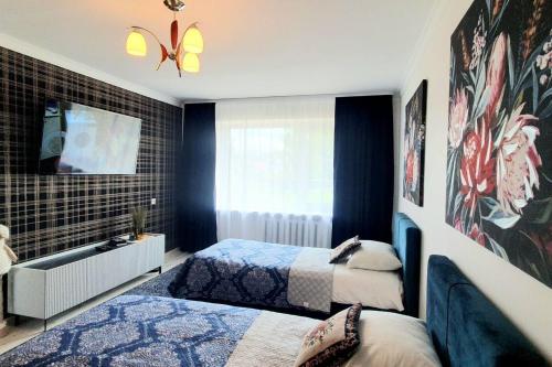 a bedroom with two beds and a tv on a wall at Studio apartment in Joniškis in Joniškis