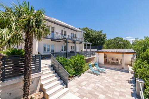a house with a patio and a palm tree at Apartmani Katica in Povile
