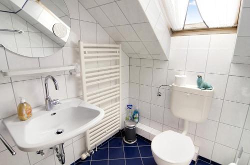 a white bathroom with a toilet and a sink at Strandhus Uiterst-hörn Utkiek in Baltrum