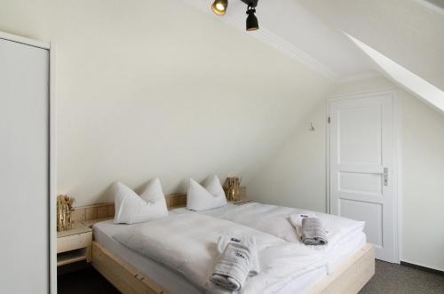a white bedroom with a bed with white sheets and pillows at Strandhus Uiterst-hörn Utkiek in Baltrum