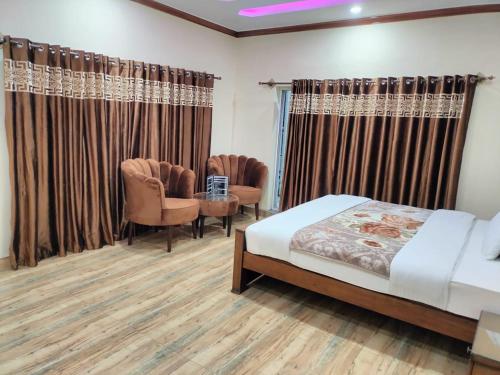 a bedroom with a bed and chairs and curtains at Unique Heights in Murree