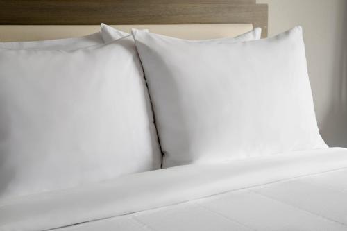 Fairfield Inn & Suites by Marriott Boston Milford في ميلفورد: اثنين من الوسائد البيضاء تقف على رأس سرير