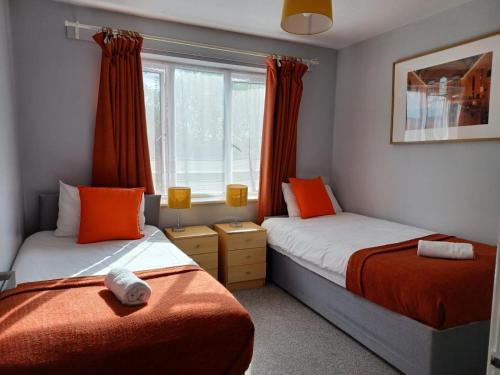 a bedroom with two beds and a window at The Maltings-Old Door - Huku Kwetu Dunstable - 2 Bedroom Apartment-Spacious Business Travelers- 2nd floor Serviced Apartment -Private Parking- Free Wifi in Dunstable