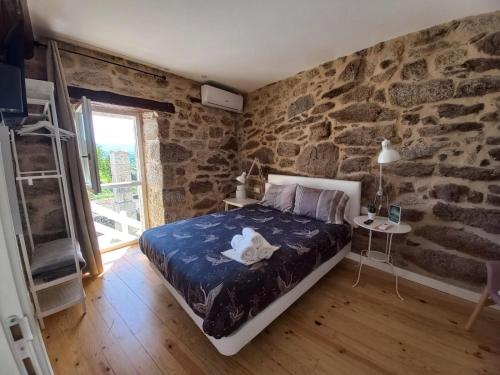 1 dormitorio con cama y pared de piedra en Pensión O Corazón da Ribeira Sacra en La Teijeira