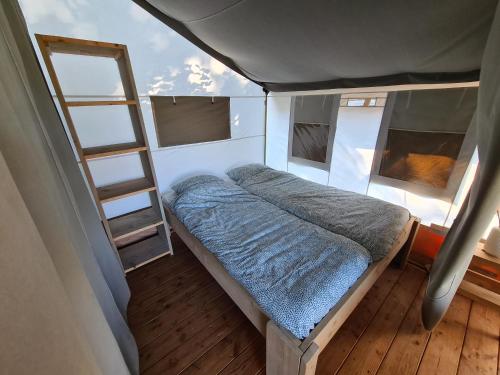 um pequeno quarto com uma cama e uma escada em Luxe kamperen bij Procamp4all em Holten