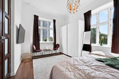 a white bedroom with a bed and a chandelier at The Modern Breakaway in Aarhus in Aarhus